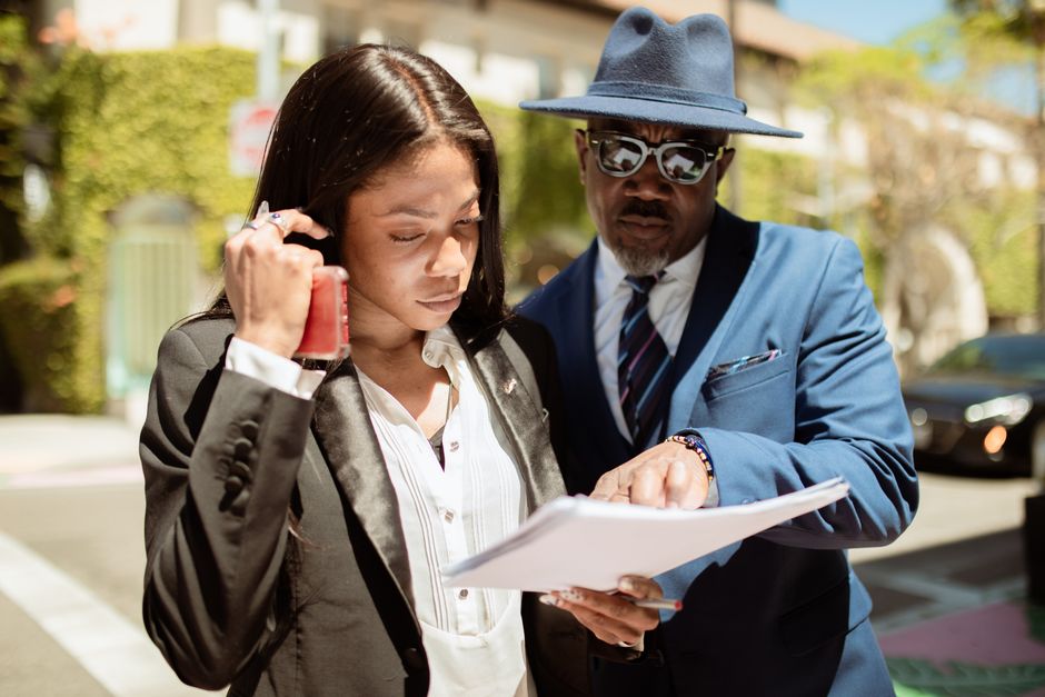 Business professionals discussing paperwork outdoors on a sunny day.